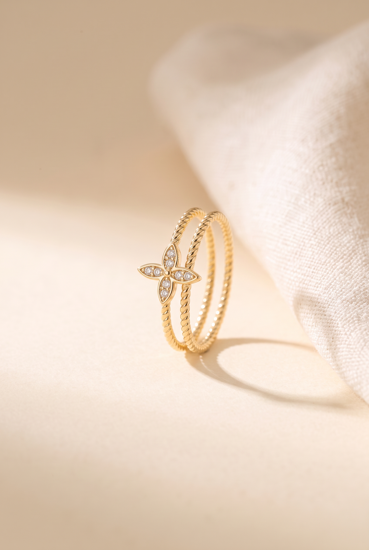 Nia Double Ring: two thin twisted rope gold bands with a small four-petal flower set with clear stones