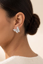 June Butterfly Earrings in White worn on the earlobe at true size: a small half-butterfly stud about 1 in across