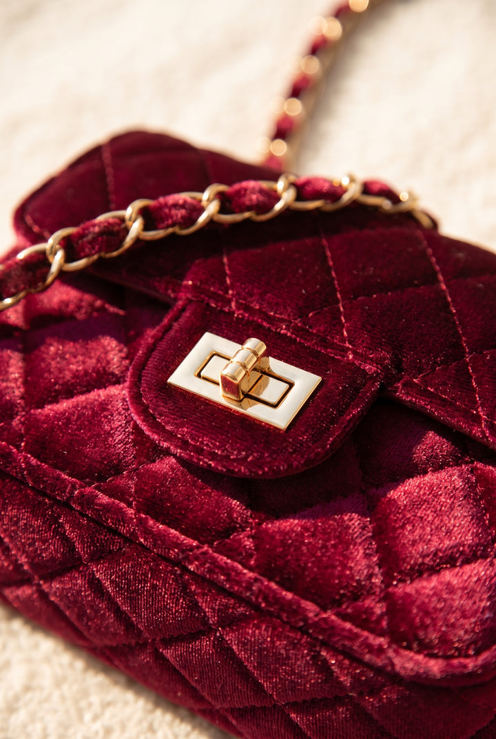 Close-up of the burgundy velvet bag's quilting and hardware