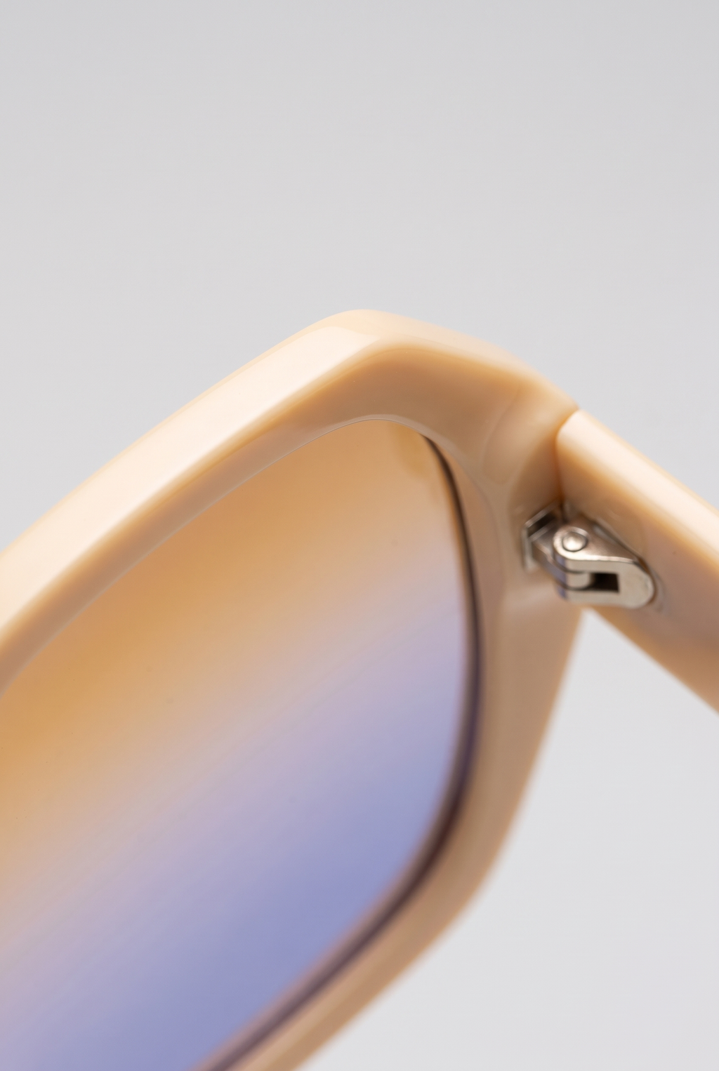 Close-up of the Haven sunglasses' cream frame corner and hinge with the amber-to-lavender gradient lens