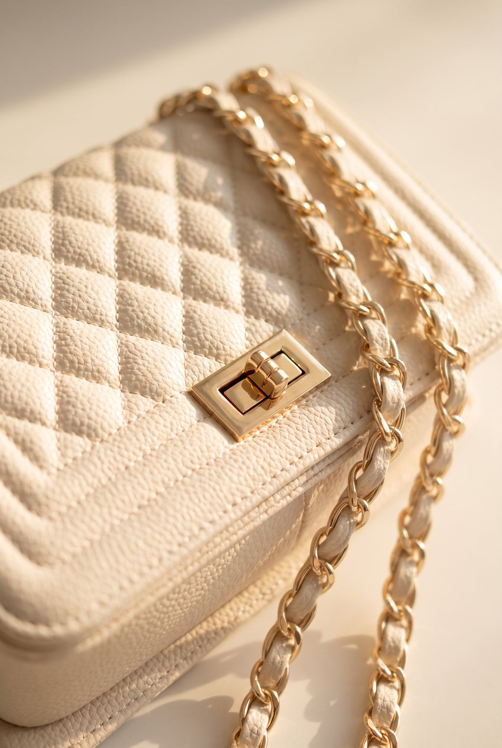 Close-up of the Jacqueline bag's beige quilted stitching, gold twist lock and chain strap
