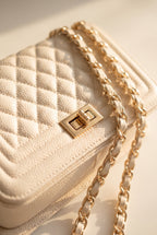 Close-up of the Jacqueline bag's beige quilted stitching, gold twist lock and chain strap