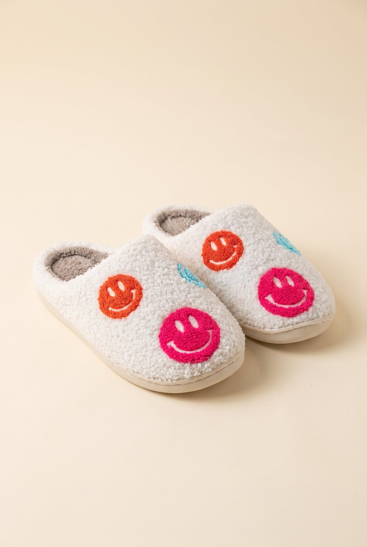 Cozy Smiley Face Slippers, pair of cream teddy fleece scuff slippers with grey lining and orange, hot pink and blue smiley patches