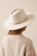 Hadley ivory felt fedora with a braided gold chain band, worn, seen from behind over a cream knit sweater