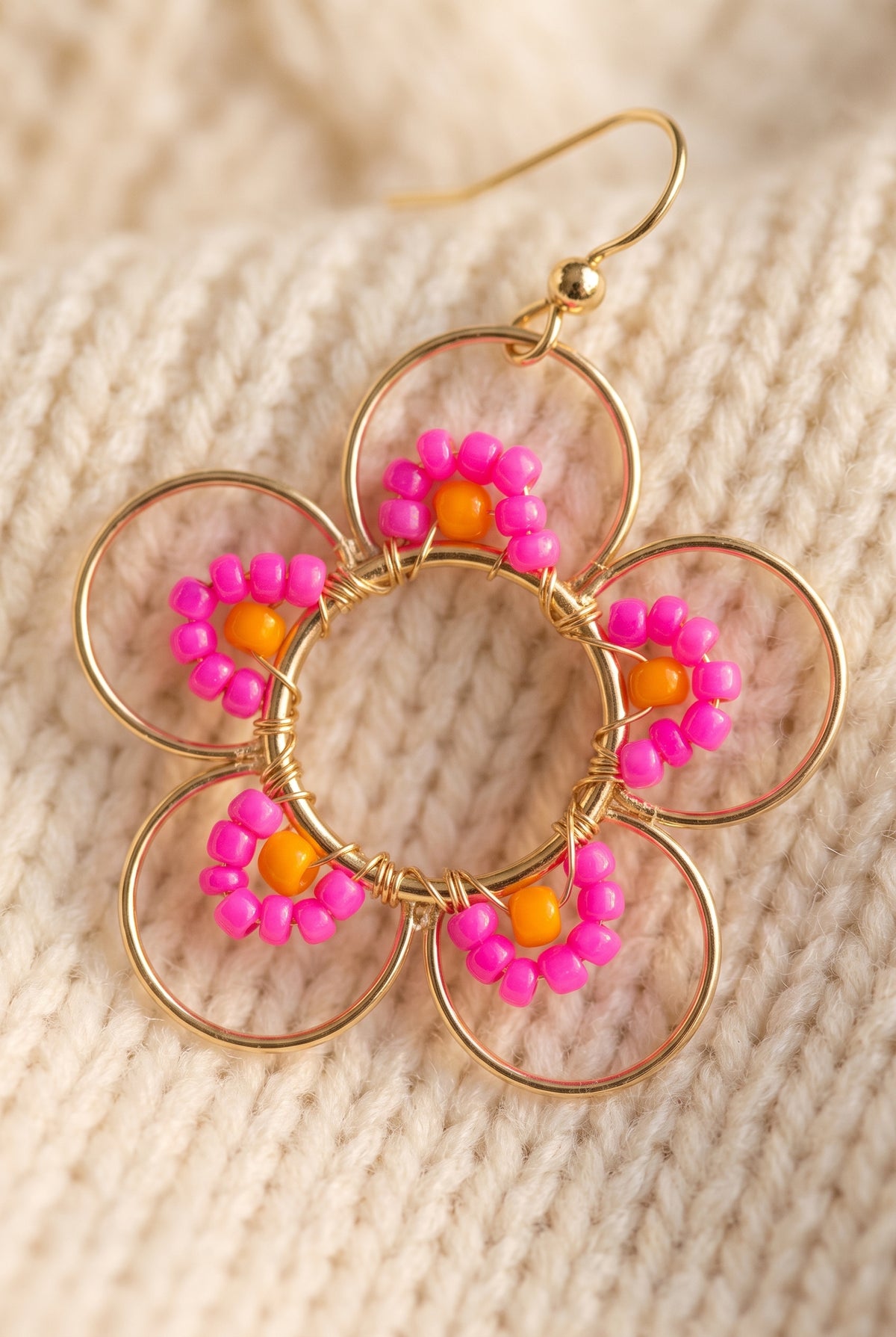 Close-up of a Hot Pink Daisy earring: five open gold wire petals, each with an arc of hot pink seed beads and an orange accent bead