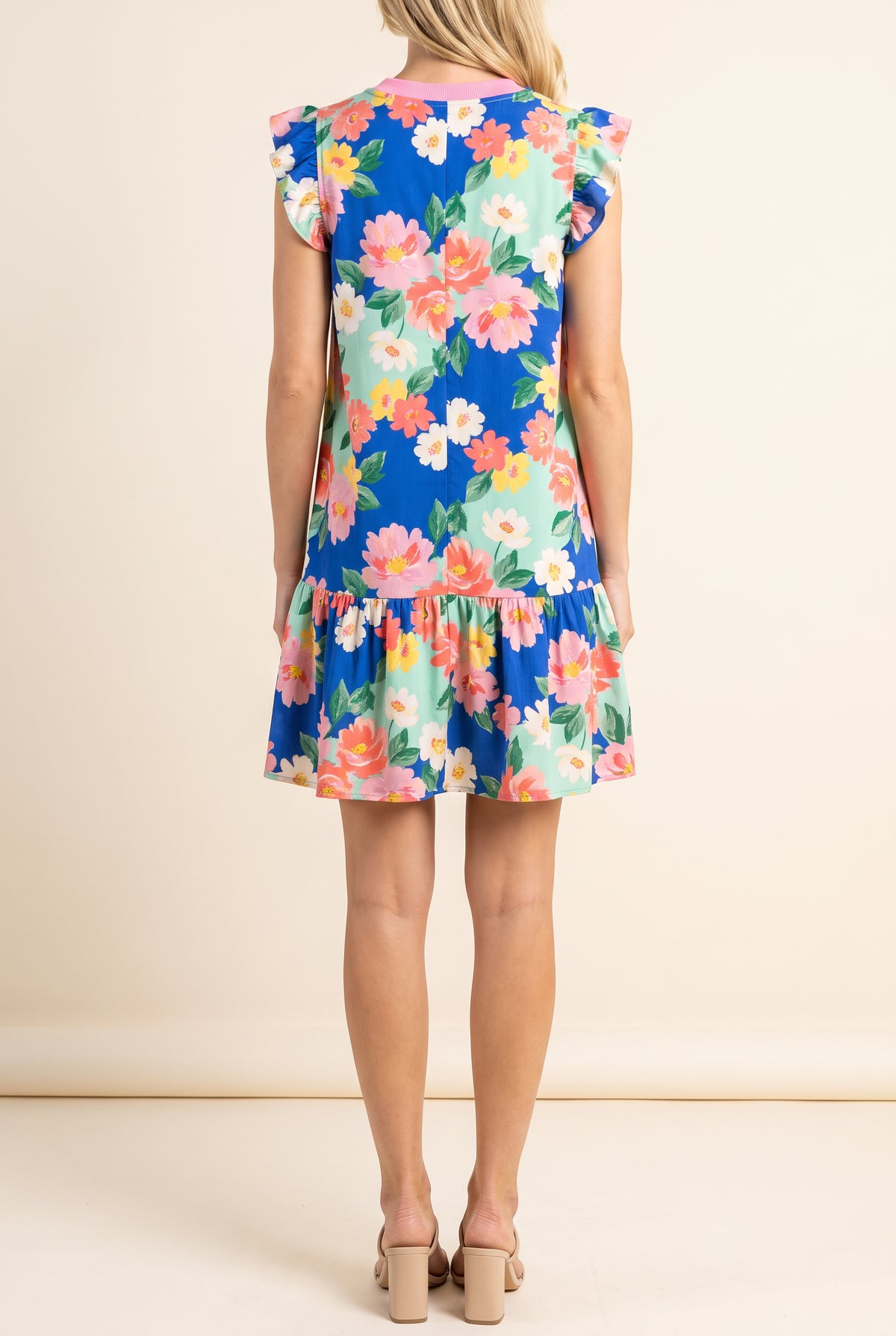 Back view of the Keep Blooming floral mini dress showing the flutter cap sleeves, pink neckband and ruffle tier hem