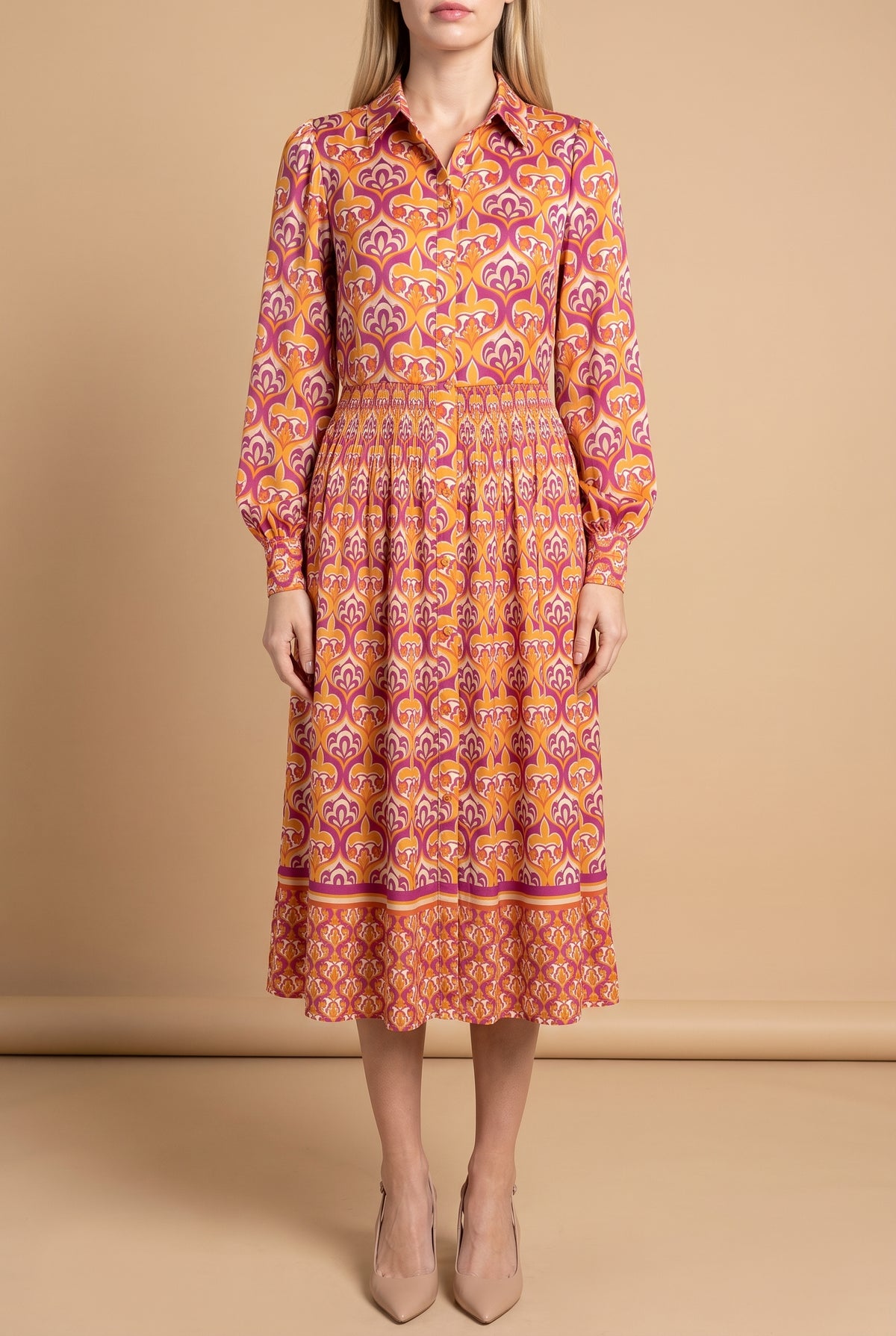Front view of the I'm Spicing Things Up printed midi shirt dress on a beige studio backdrop: collar, button front, blouson sleeves, smocked waist and border-print hem at mid-calf.