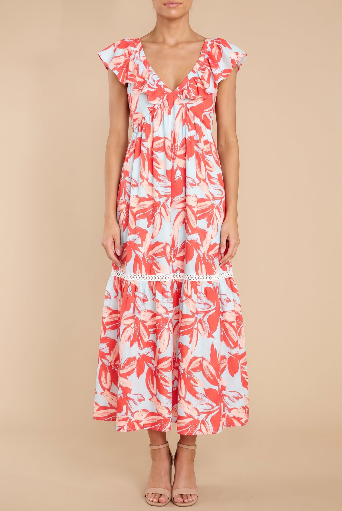 Front view of the Painted The Sky floral maxi dress on a beige studio backdrop: ruffle-edged V-neck, flutter sleeves, lace-trimmed tiers, ankle-length hem.