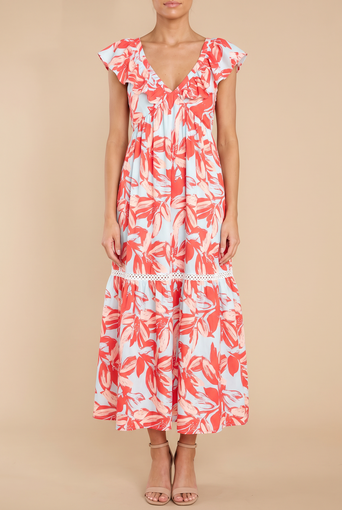 Front view of the Painted The Sky floral maxi dress on a beige studio backdrop: ruffle-edged V-neck, flutter sleeves, lace-trimmed tiers, ankle-length hem.