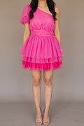 Front of the See You Again hot pink mini dress, showing the one-shoulder neckline, single sheer puff sleeve, wide pleated waistband and layered tulle skirt at mid-thigh