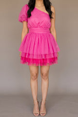 Front of the See You Again hot pink mini dress, showing the one-shoulder neckline, single sheer puff sleeve, wide pleated waistband and layered tulle skirt at mid-thigh
