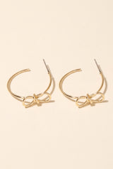 Harley Bow Tie Hoop Earrings: a pair of thin open gold hoops with a post and a sculpted gold wire bow at the front