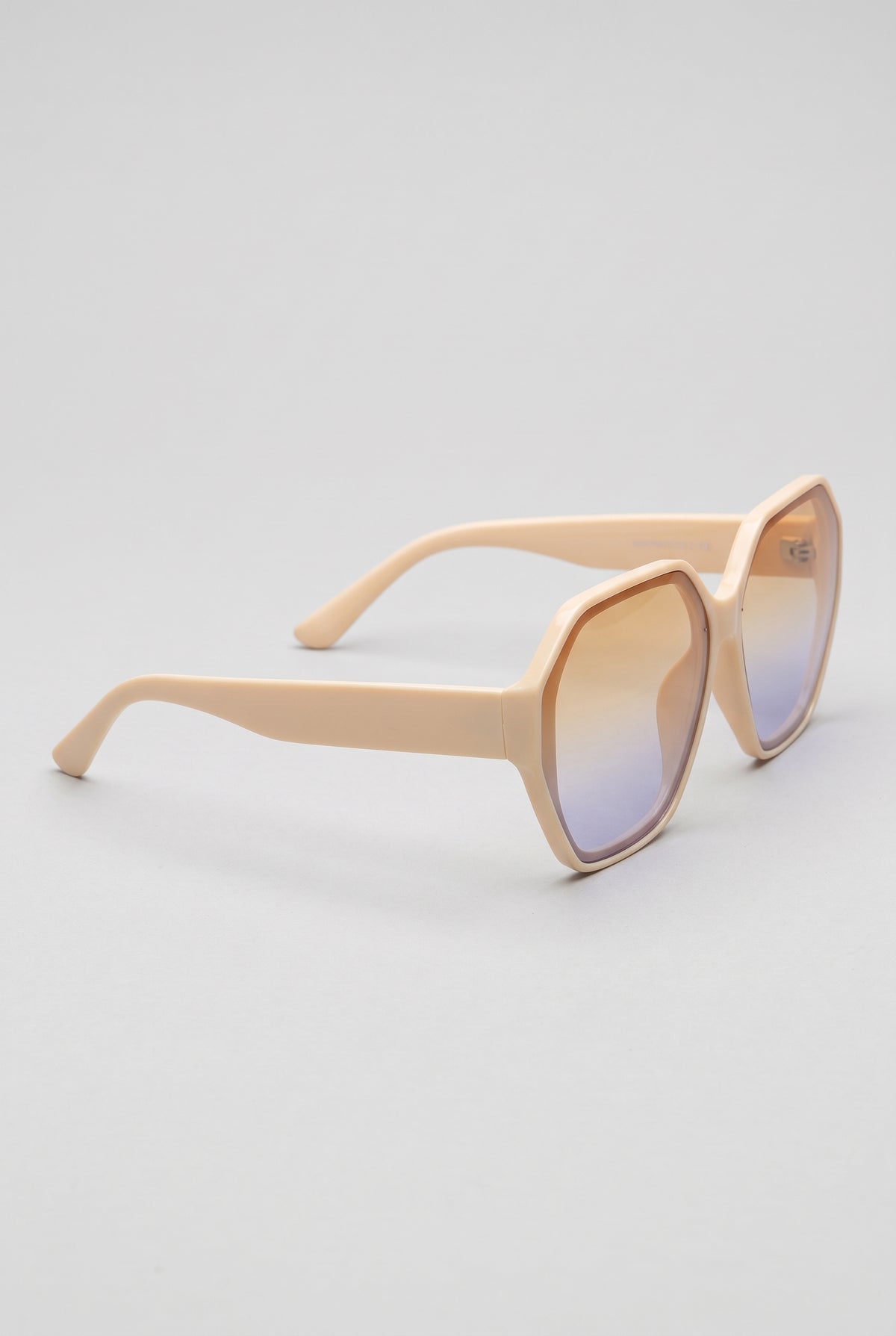 Haven oversized cream sunglasses at a three-quarter side angle showing the temple arm and hinge, on a light-grey backdrop