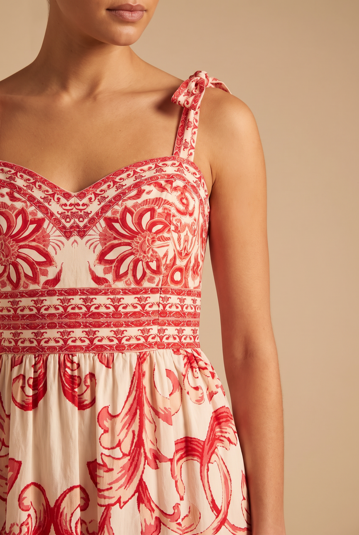 Close-up of the sweetheart neckline, tie strap bow, printed waist border and red scroll print.