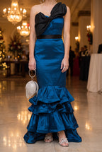 The blue satin mermaid gown styled for a holiday gala with a round rhinestone fringe bag, silver flower bow sandals and a pave X ring.