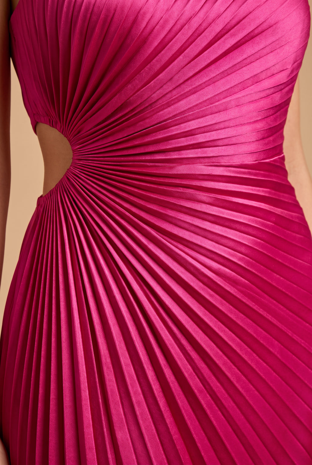 Close detail of the sunburst pleats radiating from the waist cutout on the fuchsia satin.