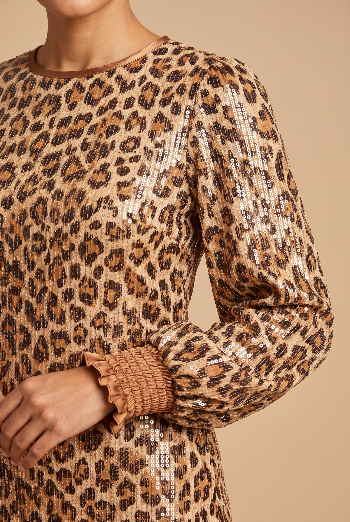 Close view of the leopard print sequins, bronze satin neckline and smocked ruffle cuff