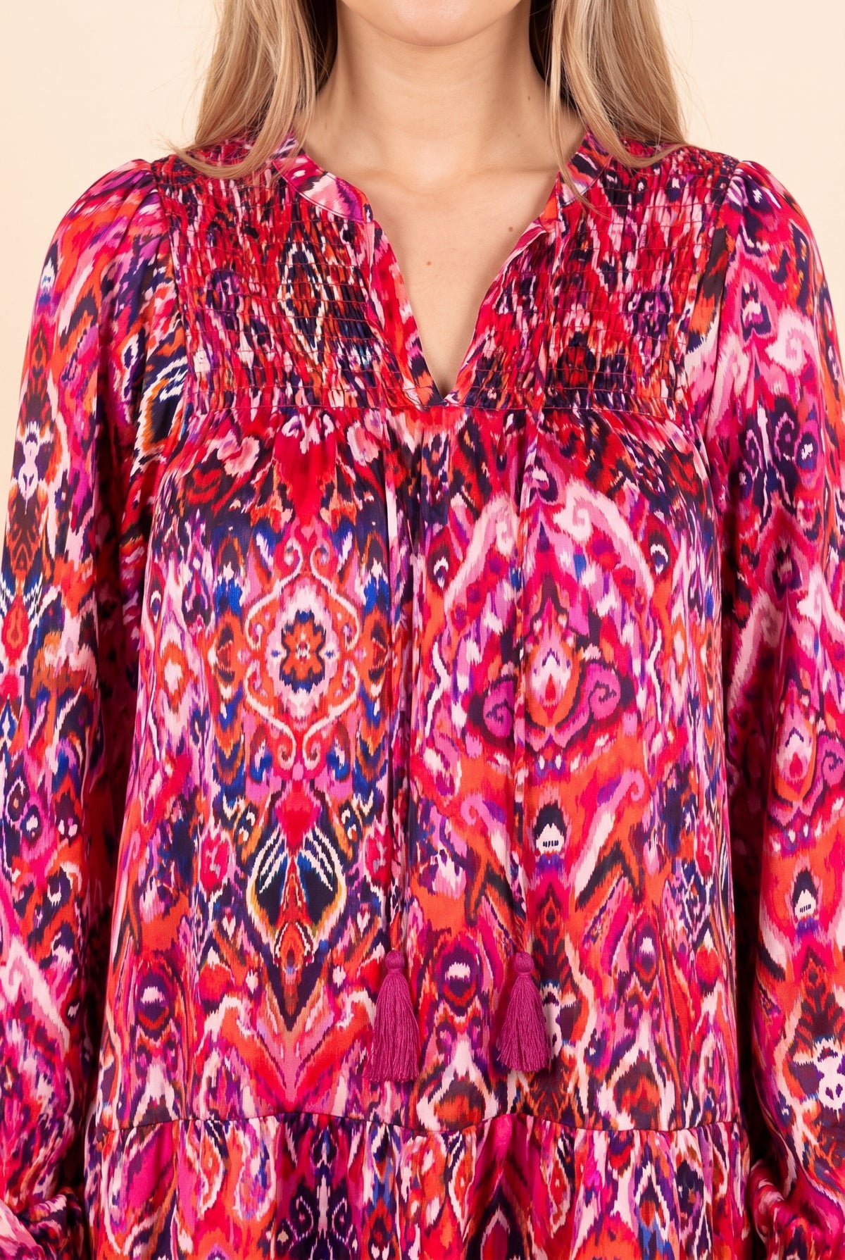 Close view of the split V-neck with tassel ties and the pink ikat style print
