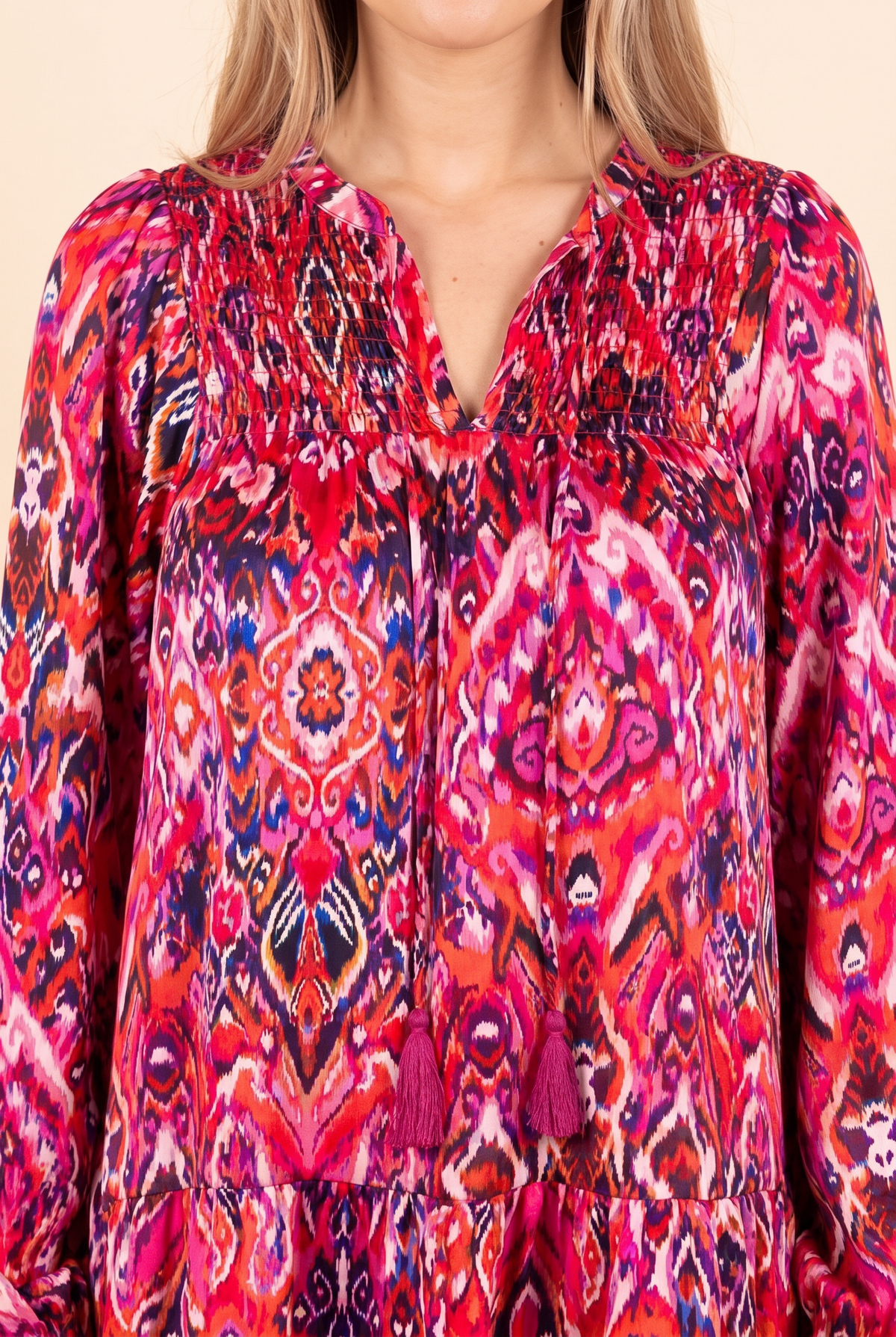 Close view of the split V-neck with tassel ties and the pink ikat style print