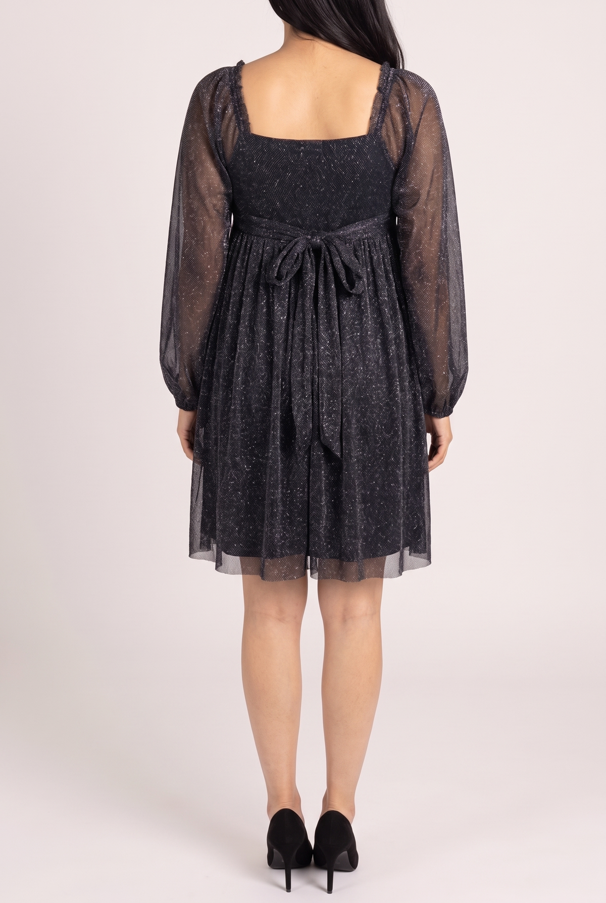 Back view of the black glitter babydoll dress showing the square back, self tie bow at the back waist, sheer sleeves and above the knee hem.