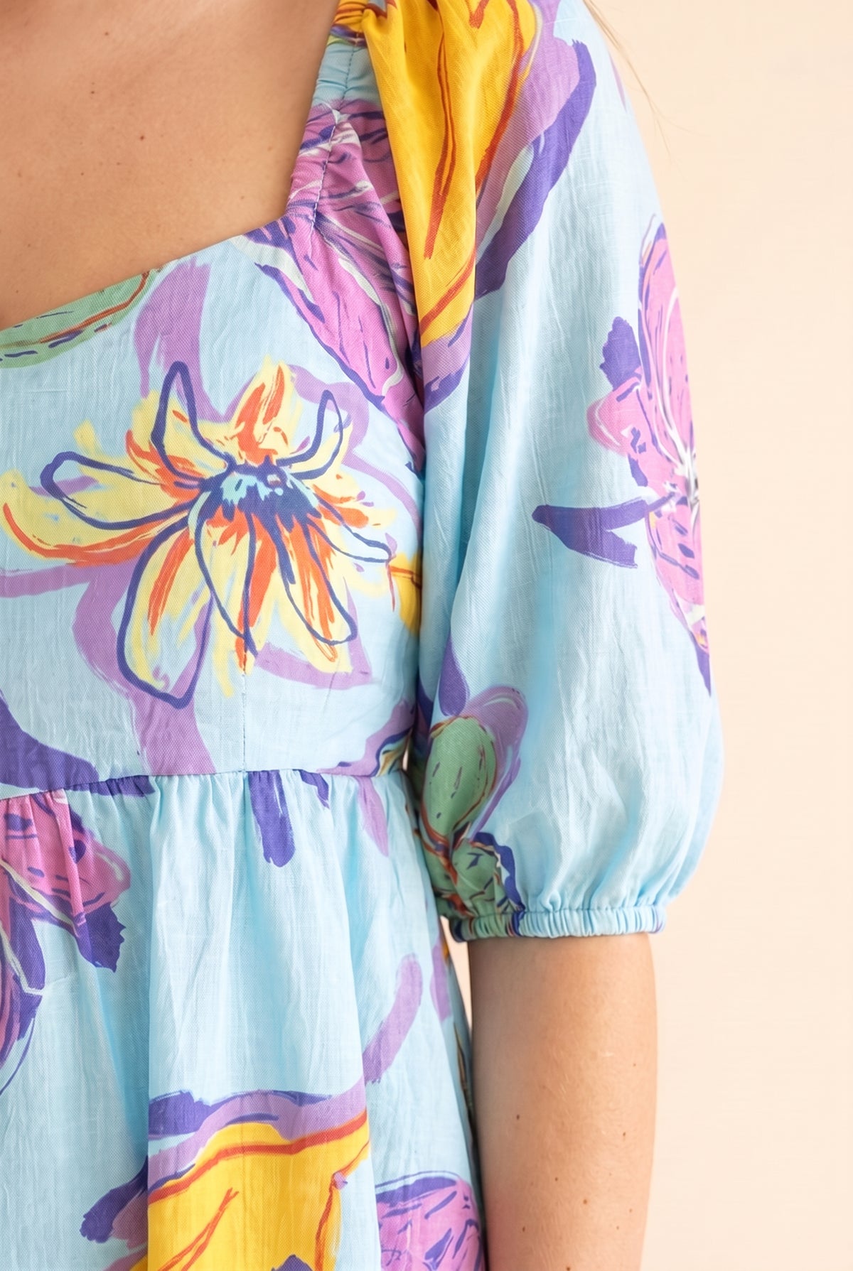 Close detail of the square neckline, puff sleeve and hand-painted floral print on aqua cotton.