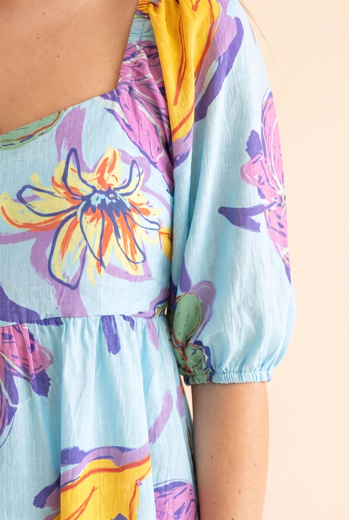 Close detail of the square neckline, puff sleeve and hand-painted floral print on aqua cotton.