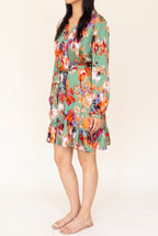 Side view of the green abstract print satin dress showing the V neck, tie belt, balloon sleeve and ruffle hem.