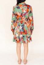 Back view of the green abstract print satin dress showing the balloon sleeves, tie belt at the high waist and ruffle hem above the knee.