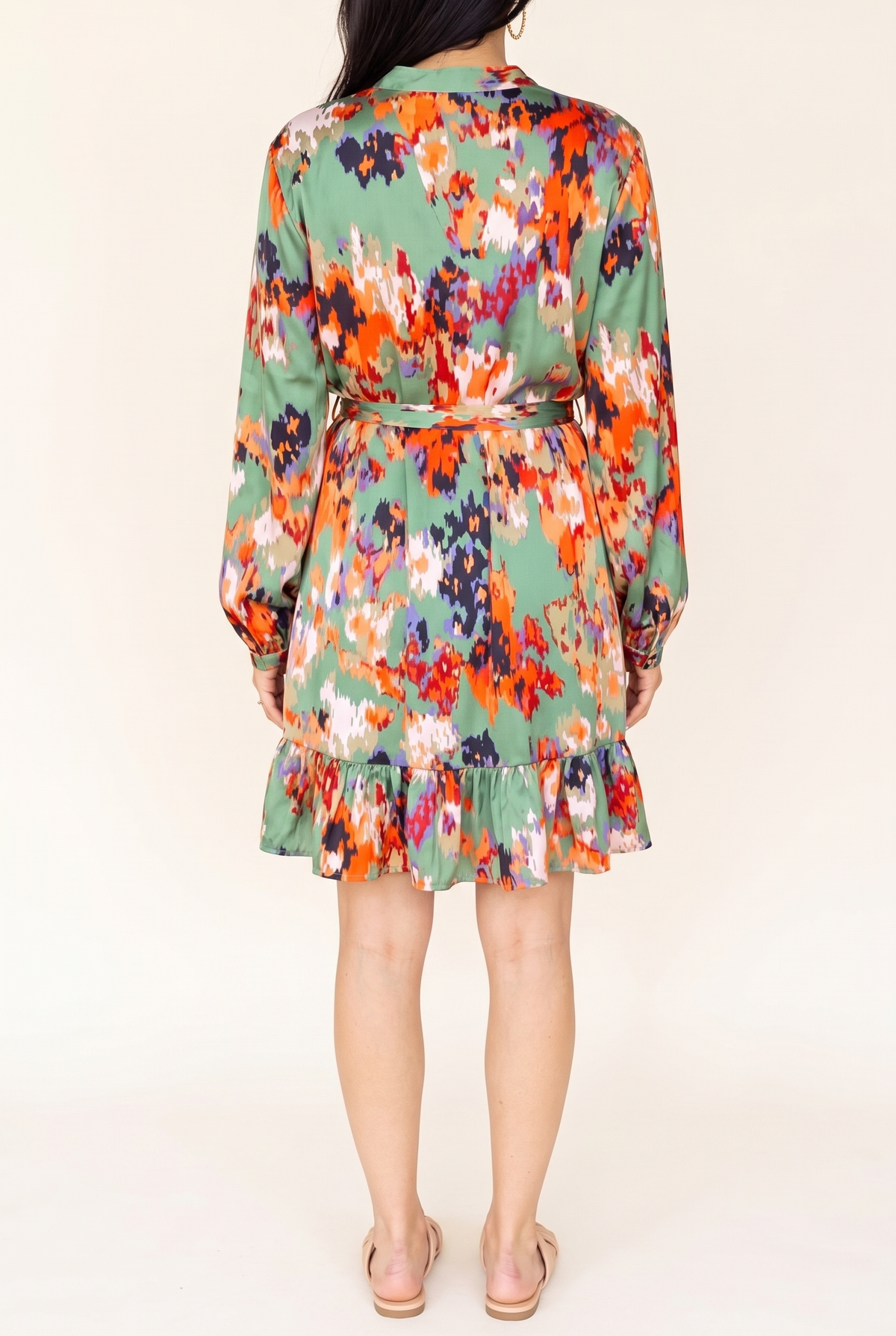 Back view of the green abstract print satin dress showing the balloon sleeves, tie belt at the high waist and ruffle hem above the knee.