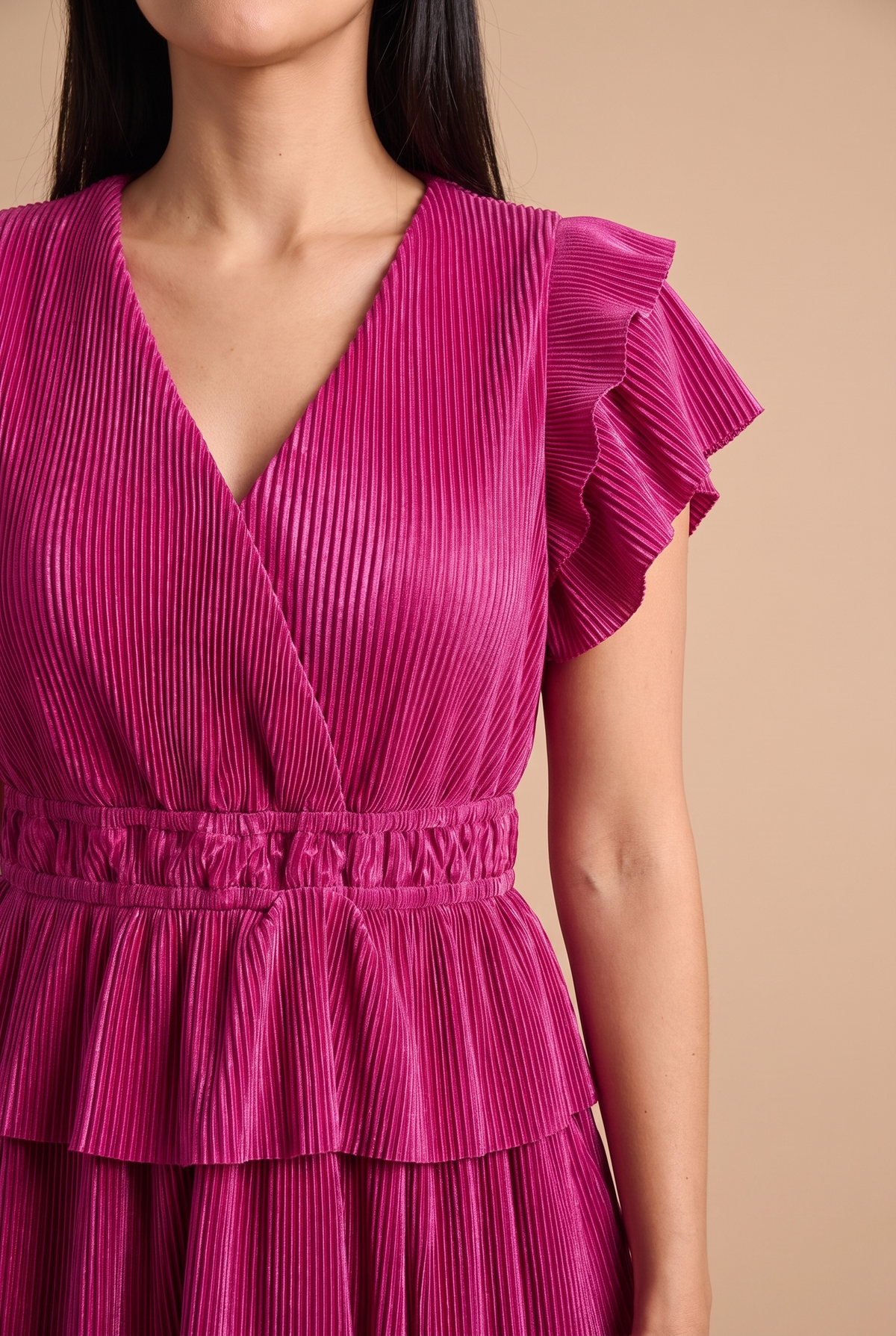 Close-up of the fine plisse pleats, surplice V neckline, flutter sleeve and smocked elastic waistband.
