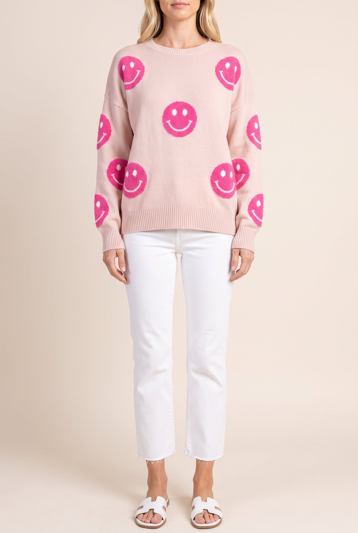 Front of the Cuteness Overloaded pink happy face sweater worn untucked, showing the fuzzy hot pink smiley faces on body and sleeves.