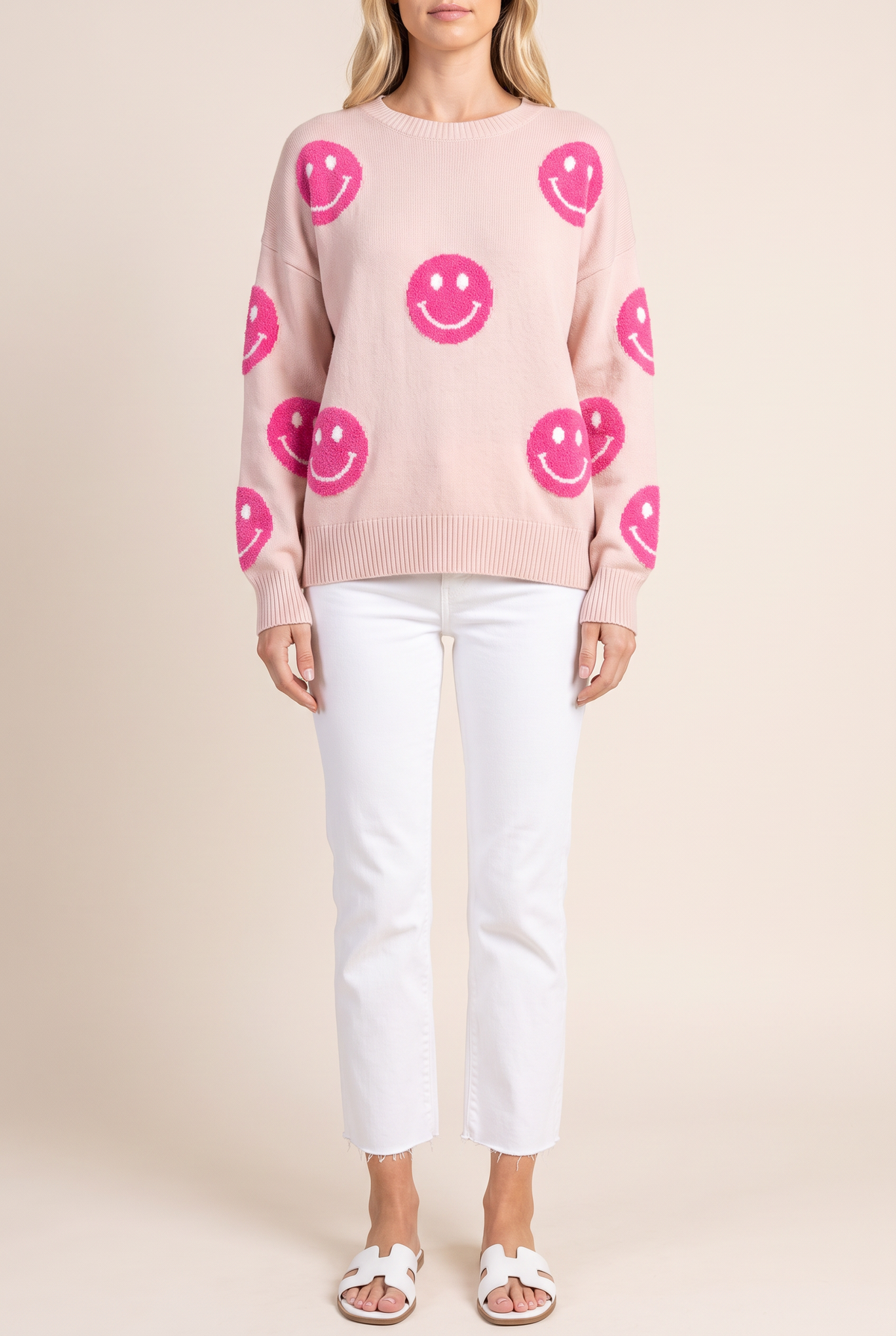 Front of the Cuteness Overloaded pink happy face sweater worn untucked, showing the fuzzy hot pink smiley faces on body and sleeves.
