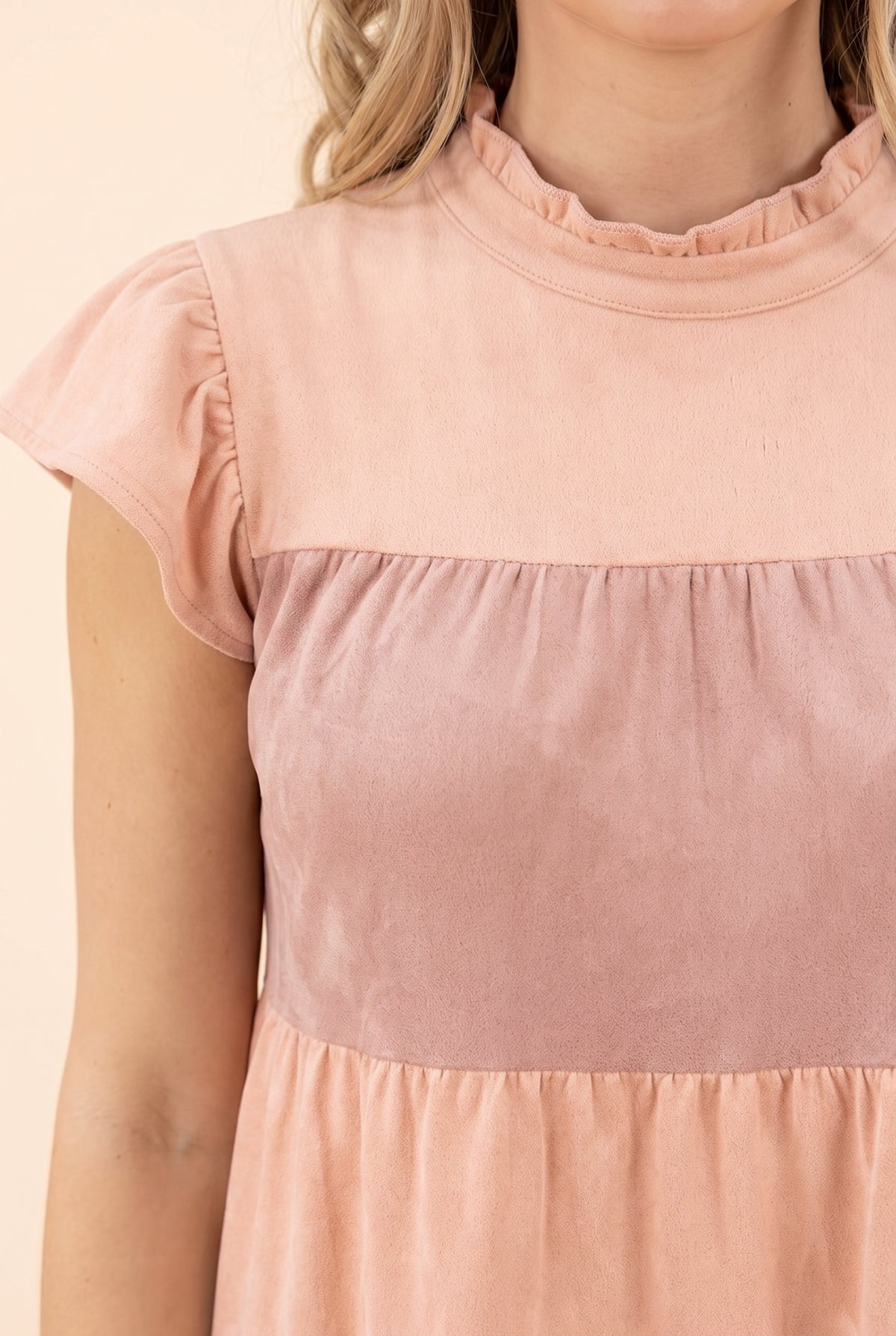 Close detail of the ruffled mock neck, flutter sleeve and brushed faux suede color-block tiers.