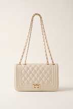 Jacqueline beige quilted vegan leather shoulder bag with gold chain strap and twist lock, on a plain studio background
