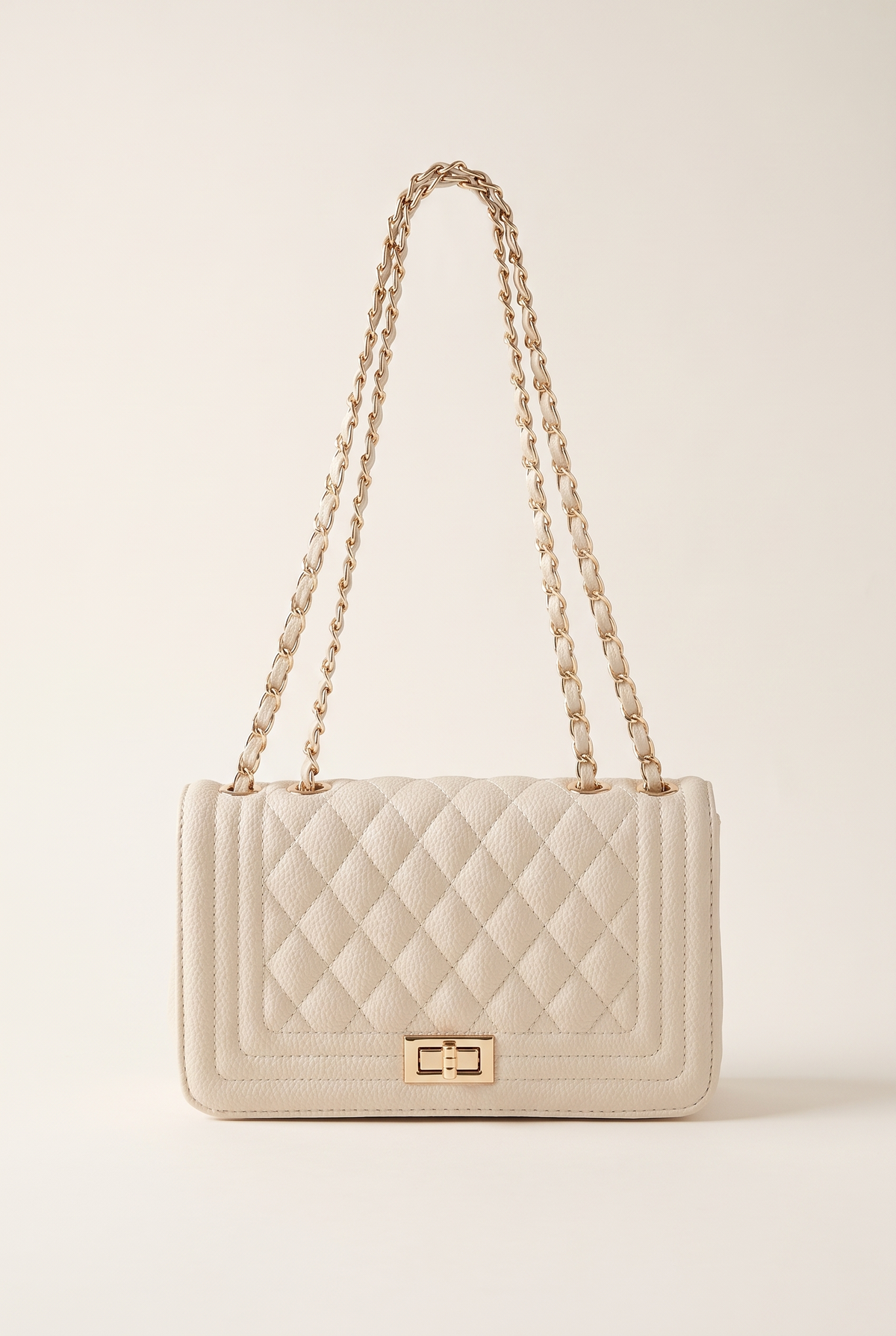 Jacqueline beige quilted vegan leather shoulder bag with gold chain strap and twist lock, on a plain studio background