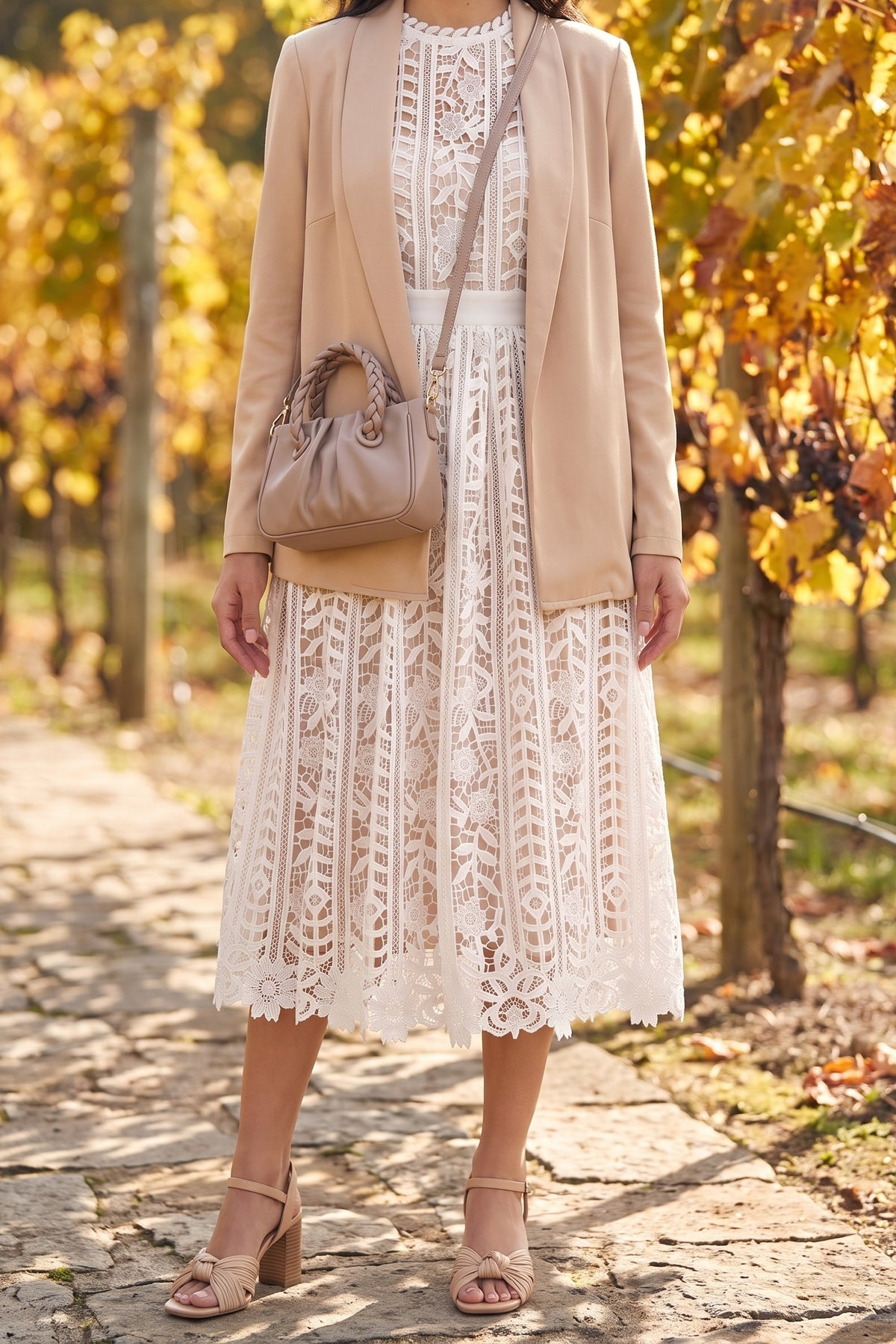 White lace midi dress styled for an autumn vineyard stroll with a camel cardigan blazer, nude pleated bow sandals and a taupe crossbody bag.
