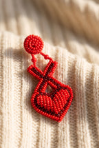 Close-up of the X and heart earring: red seed beads with rows of dark red rhinestones