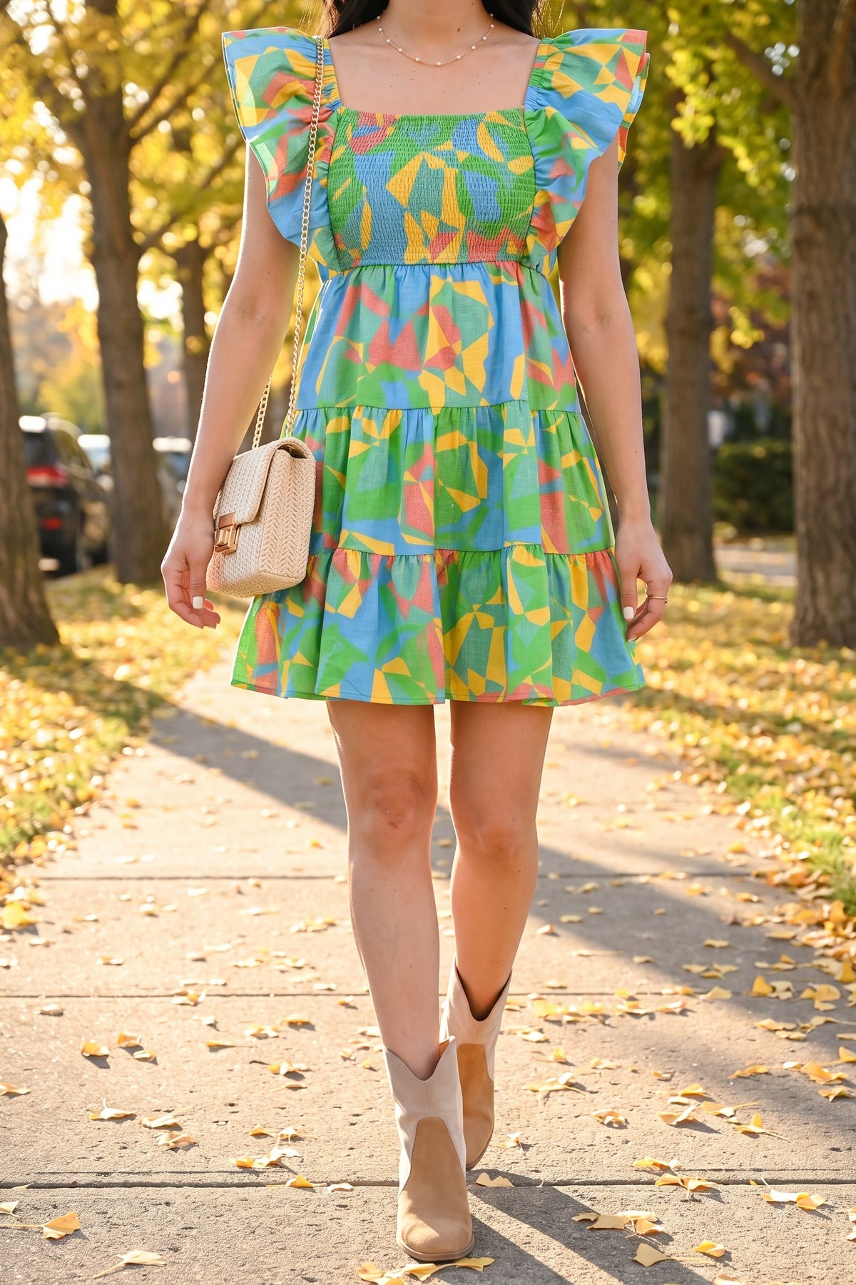 Radiant As Always flutter sleeve mini dress styled for fall with Sadie tri-tone booties, the cream Vivian crossbody and the Kate pearl necklace on a leafy sidewalk.