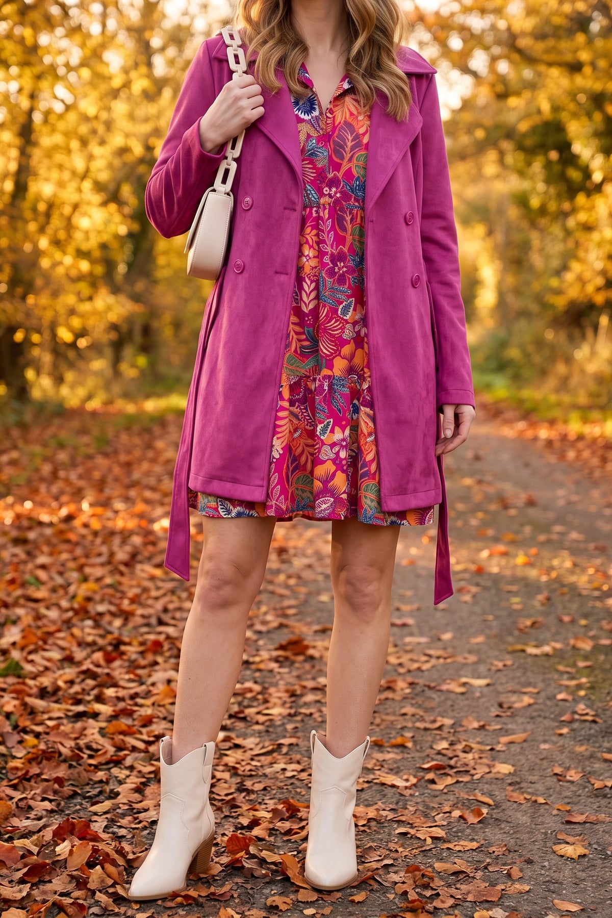 Magenta floral mini dress styled for fall with a magenta suede trench coat worn open, a cream chain shoulder bag and cream western ankle boots