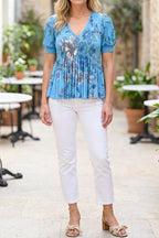 Model wearing the blue floral V-neck pleated top, shown from the chin down
