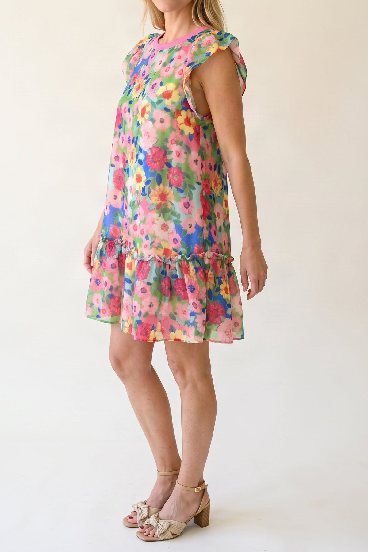 Model wearing the bright floral flutter-sleeve mini dress, shown from the chin down