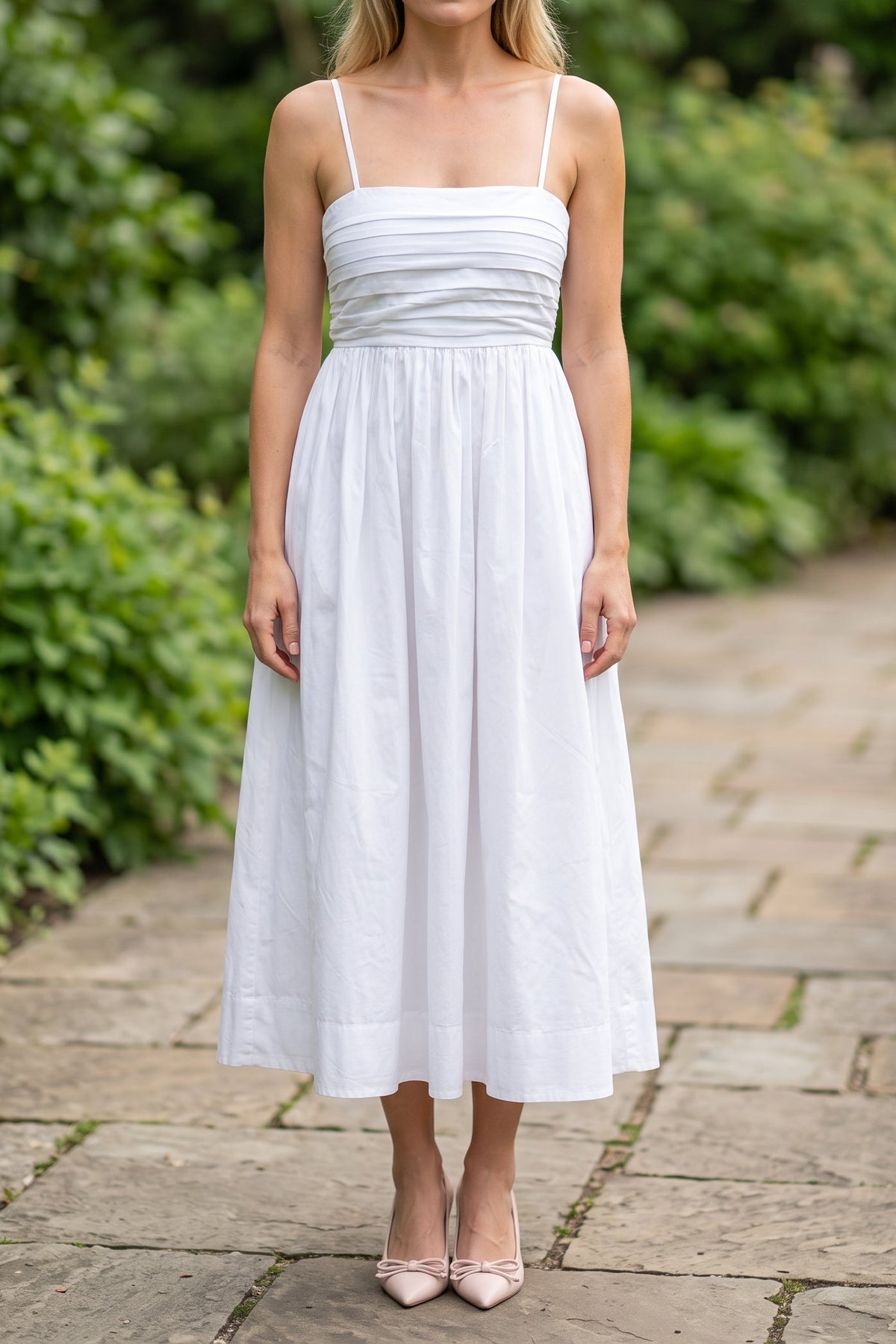 Model wearing the Love Actually white pleated midi dress outdoors, from the chin down