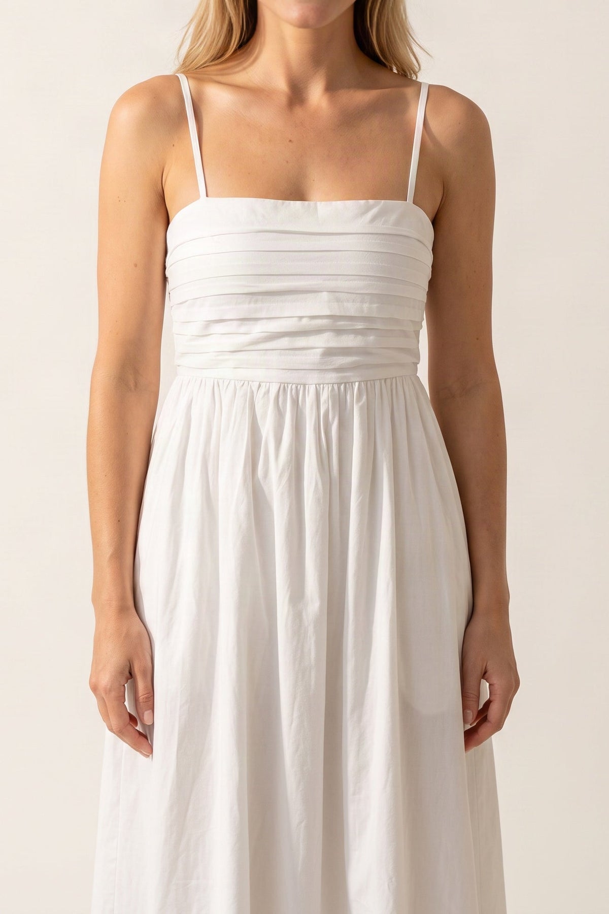 Model wearing the Love Actually white pleated midi dress, shown from the chin down