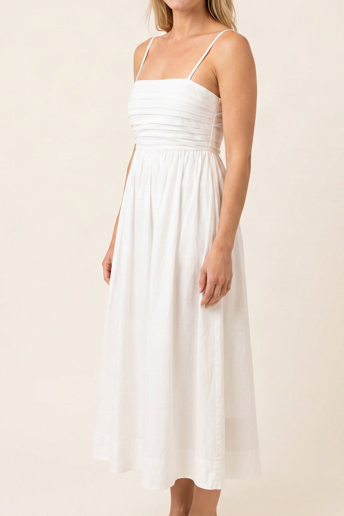 Model wearing the Love Actually white pleated midi dress, side view from the chin down