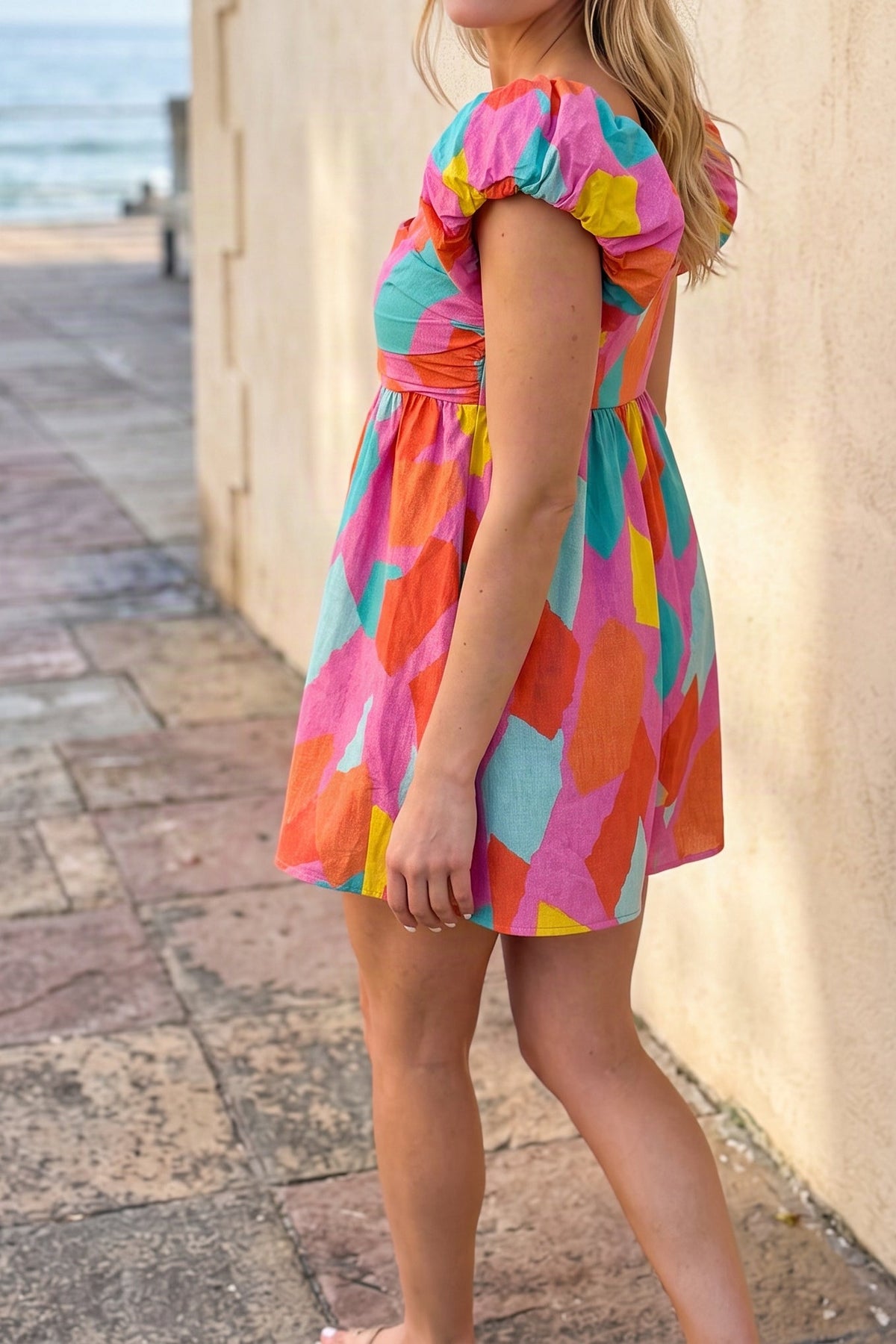 Model wearing the multicolour print puff-sleeve romper dress, side view from the chin down