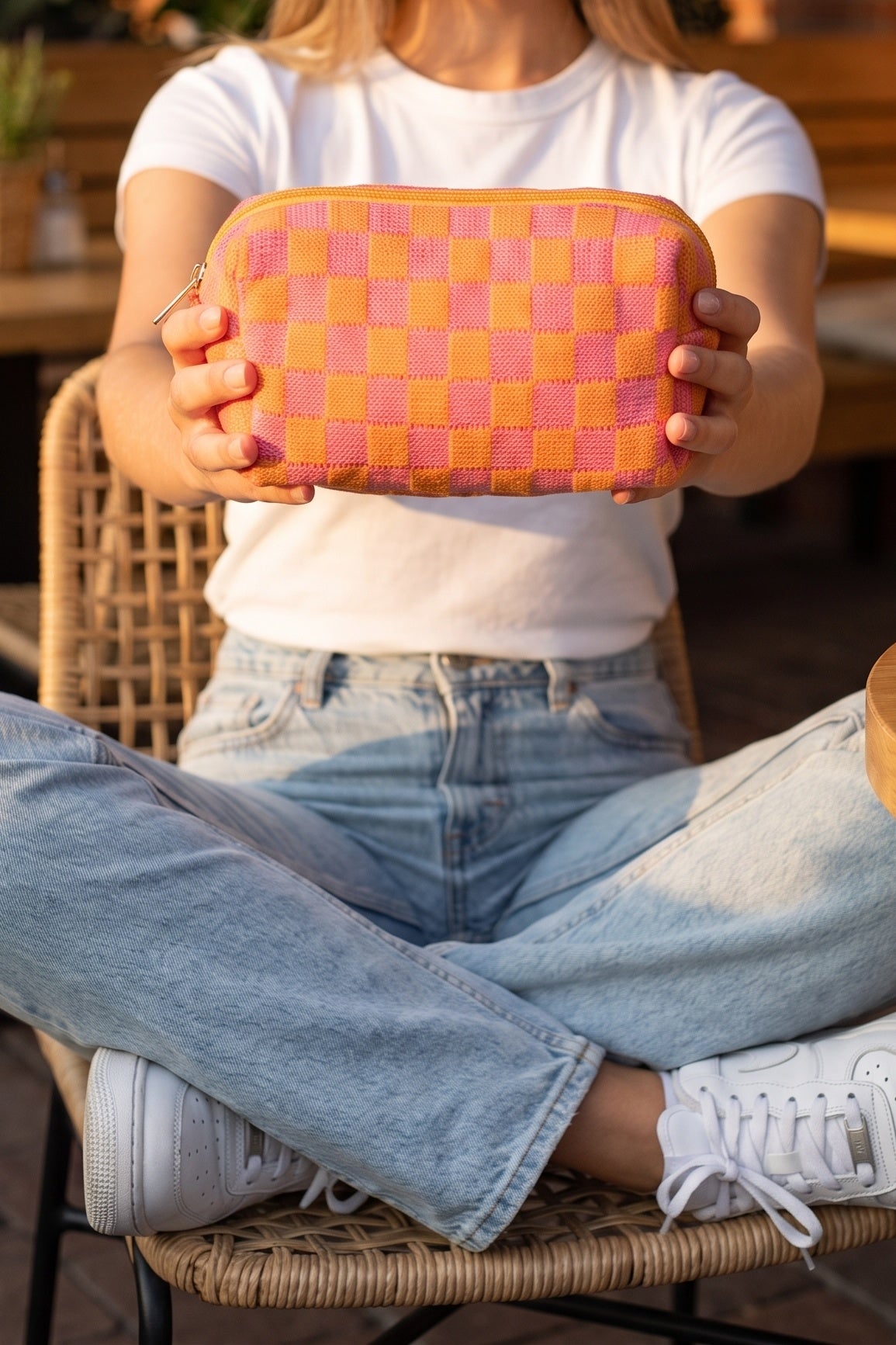 Check Yourself Cosmetic Bag in Orange held out in both hands by a seated model, shown chin down