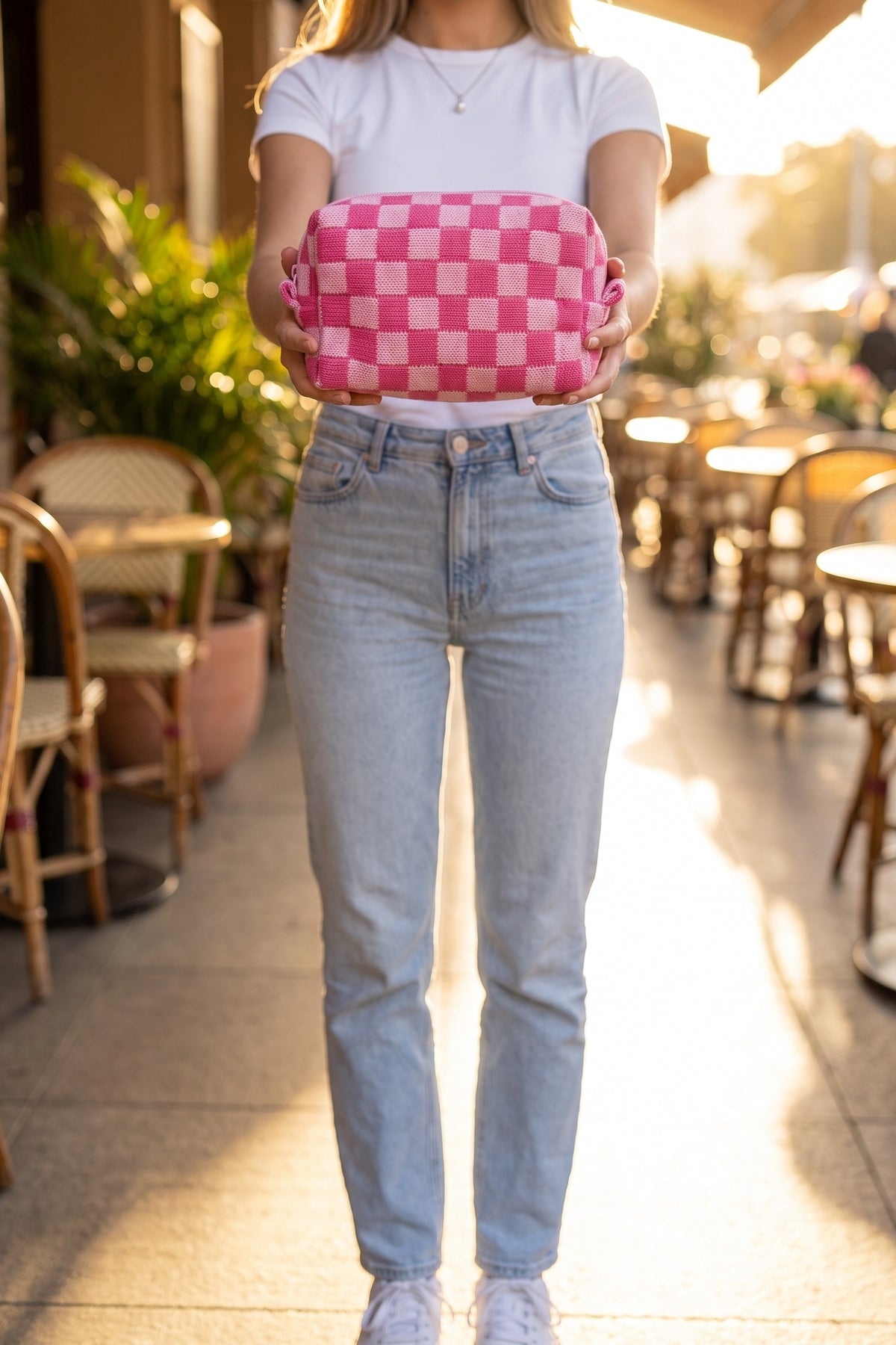 Check Yourself Cosmetic Bag in Pink held in both hands at the waist, shown chin down with a white tee and jeans