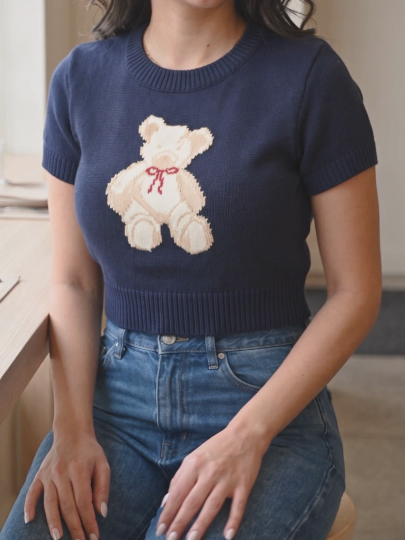 Shweta moving while seated in the navy teddy bear sweater top, showing the Small cropped fit.