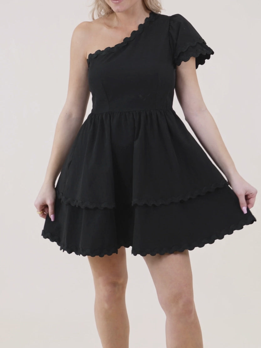 Elsa moves in the black mini dress to show the polyester give and tiered skirt swing.