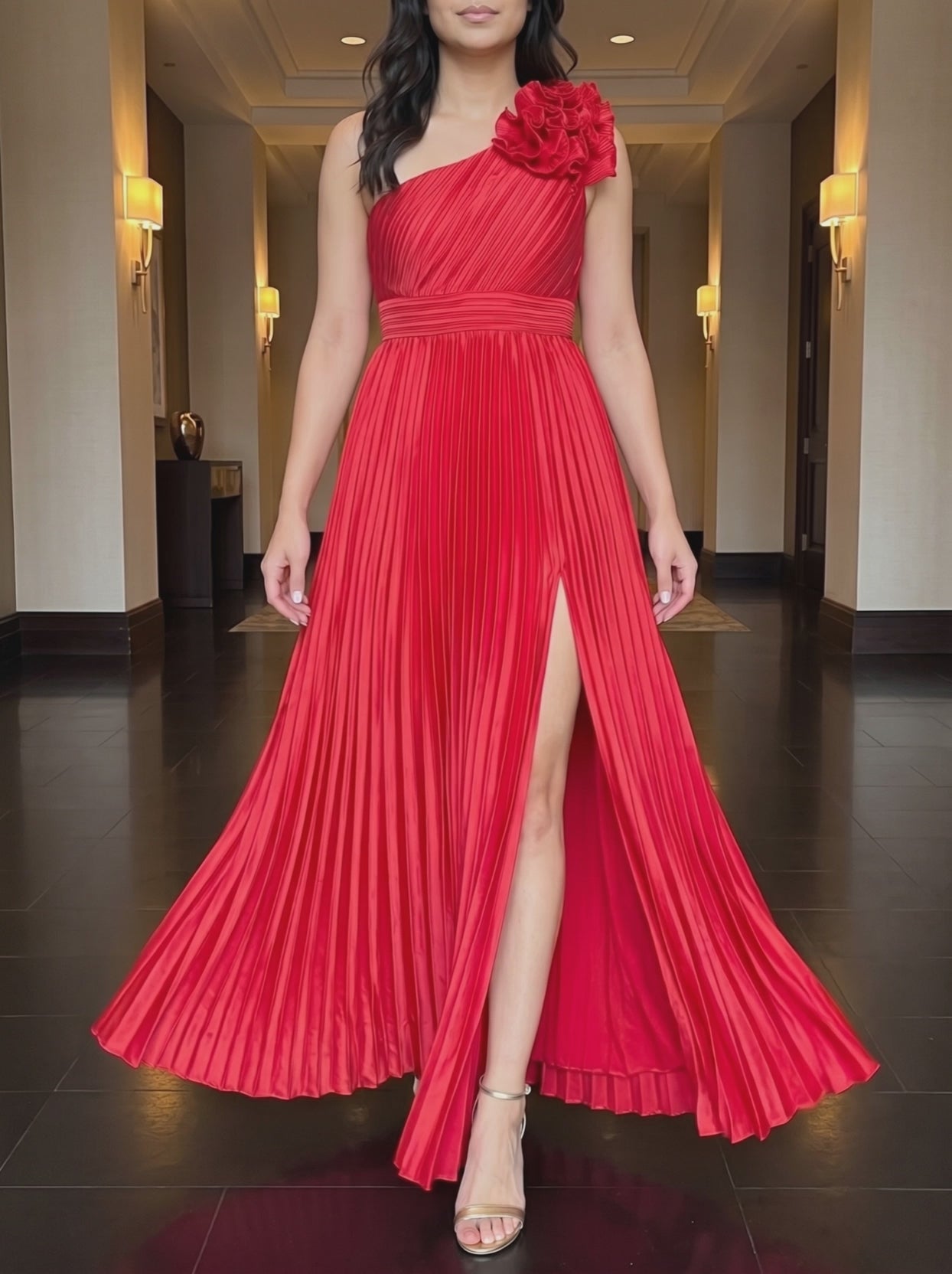 Red One More Night maxi dress worn in a warm hotel corridor, framed from the chin down, walking forward as the pleated skirt and slit move.